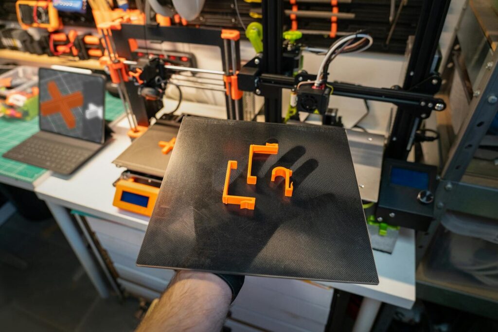 Close-up of a 3D printer and printed parts in a modern workshop setting.